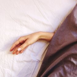 High angle view of cropped hand on bed