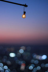 Illuminated light bulb against sky at night