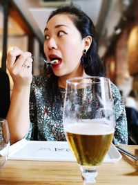 Midsection of woman drinking glass on table at restaurant