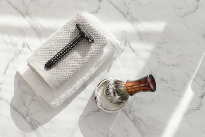 Directly above shot of shaving brush and razor on marble floor