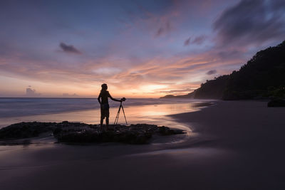 Silhouette man standing on beach against sky during sunset