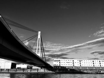 Bridge over river against sky in city