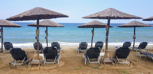 Deck chairs on beach against sky