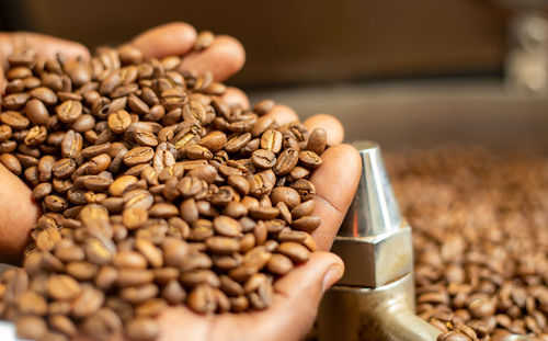 Close-up of roasted coffee beans in hands  