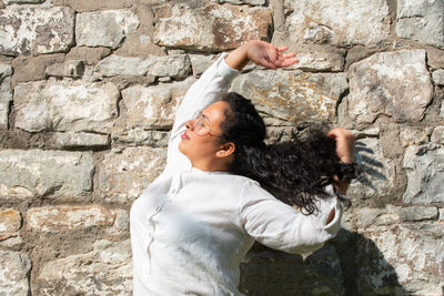 Side view of woman standing against stone wall