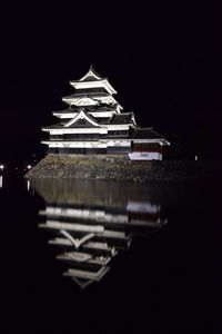 Illuminated building by lake at night