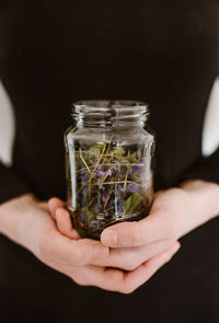 Midsection of women holding plants in jar