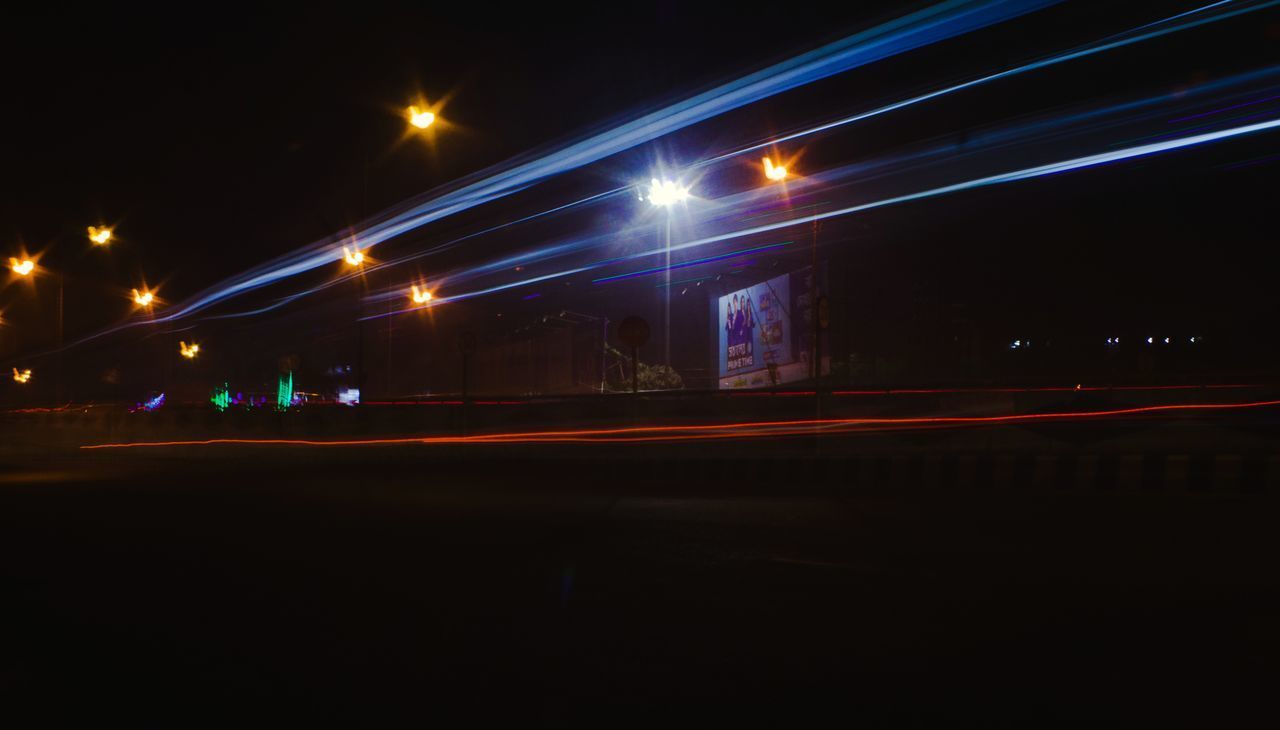 ILLUMINATED LIGHT TRAILS ON STREET AT NIGHT