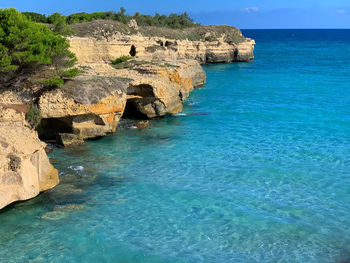 Rock formations by sea against blue sky at the salento coast of puglia