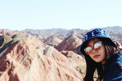 Portrait of young woman in sunglasses against mountains