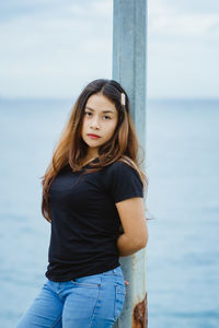 Portrait of young woman standing against sea