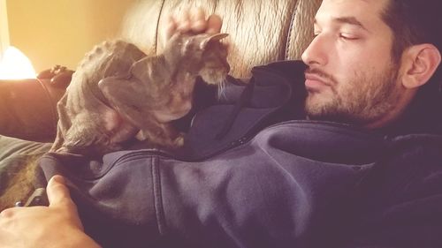 Close-up of man with dog on sofa at home
