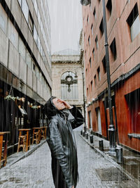 Rear view of man standing on footpath amidst buildings