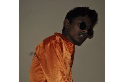 Young man wearing sunglasses against wall at home