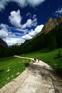 People on landscape against cloudy sky