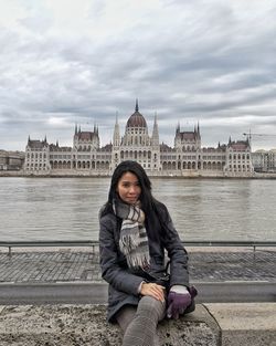 Portrait of woman sitting against parliament building