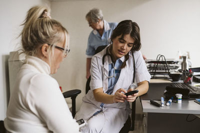 Female healthcare worker discussing over glaucometer with patient in medical clinic