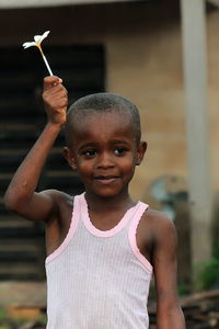 Wet smiling boy holding flower during rainy season