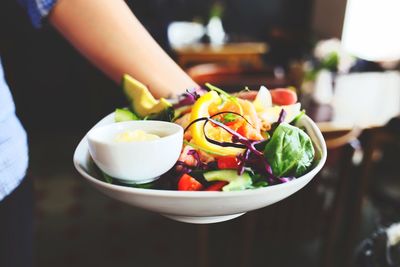 Cropped image of waiter holding fresh salad plates at restaurant