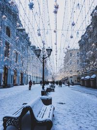 Man walking on snow covered city against sky