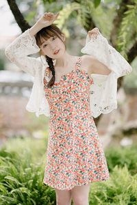 Young woman standing against plants