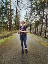 Full length of woman standing amidst trees in forest