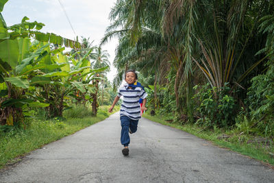 Full length portrait of boy running on road 