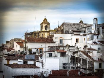 Houses in town against cloudy sky