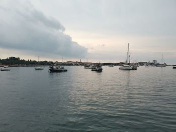 Sailboats in sea against sky during sunset