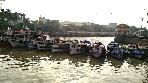 Boats moored at harbor against clear sky