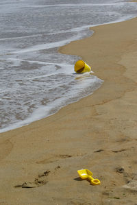 Forgotten yellow toy on empty beach 