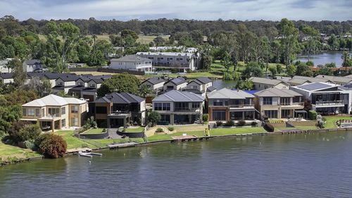 Buildings by river against sky