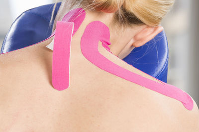 Rear view of mature woman with pink kinesio tape on back