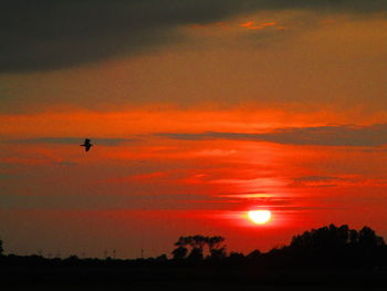 Scenic view of silhouette landscape against orange sky