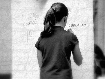 Rear view of woman standing against wall