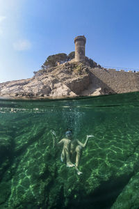 People swimming in sea against clear blue sky