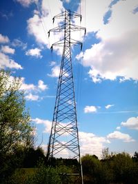 Low angle view of electricity pylon against cloudy sky