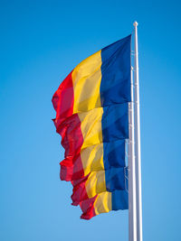 Low angle view of flag against clear blue sky