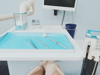 Patient sitting below tray of dental tools at clinic