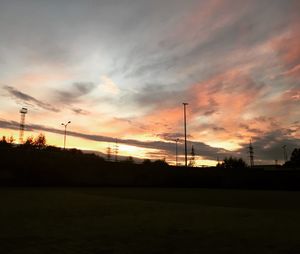 Silhouette of electricity pylons against dramatic sky