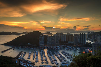 High angle view of cityscape by sea against sky during sunset