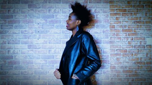 Young woman standing against brick wall