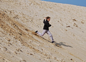 Full length of boy running on sand dunes