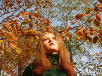 Woman looking away against trees in sunny day