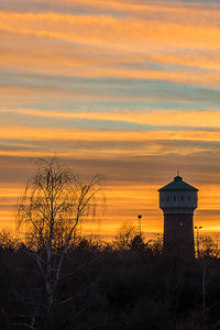 Silhouette of building against orange sky