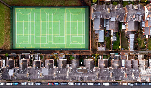 Aerial view above rooftops of back to back terraced houses with local community sports pitch 