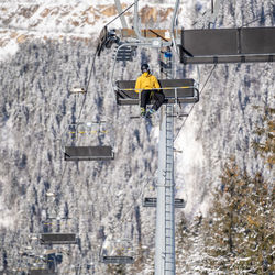 Low angle view of a man on a ski lift with the slopes in the background