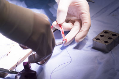 Cropped hands of doctor cutting stitches over table