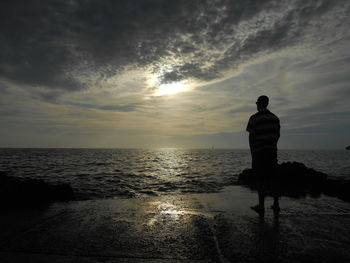 Silhouette of man at beach against sky during sunset