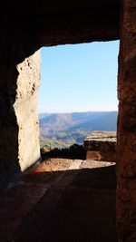 Stone wall against sky seen through arch